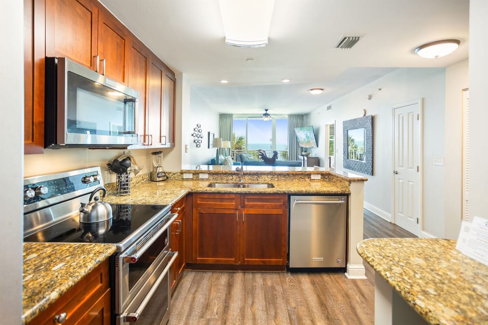 Your fully equipped kitchen features granite countertops, stainless steel appliances, and warm wood cabinetry, perfect for preparing meals during your stay.