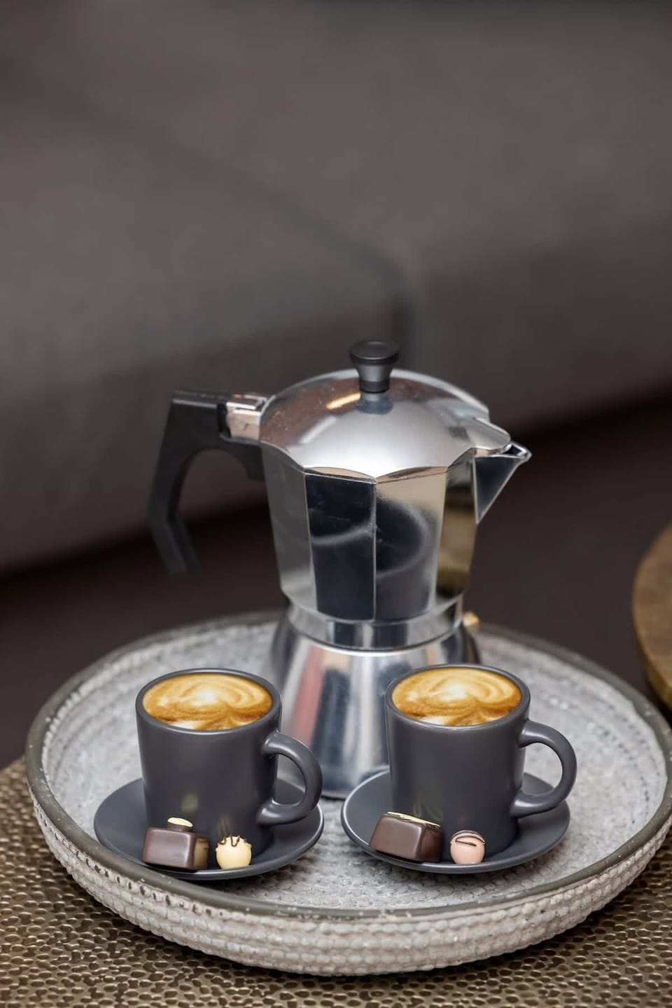 A close-up of a decorative coffee table with a metal top, adorned with candles and a modern vase.