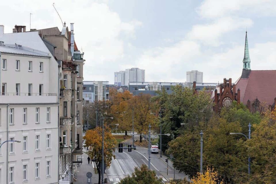 A picturesque view of a city street with classic European architecture and trees in warm autumn hues.