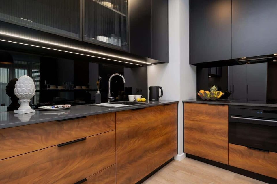 A stylish kitchen with sleek wooden cabinetry, black countertops, and modern appliances, connected to the dining area.