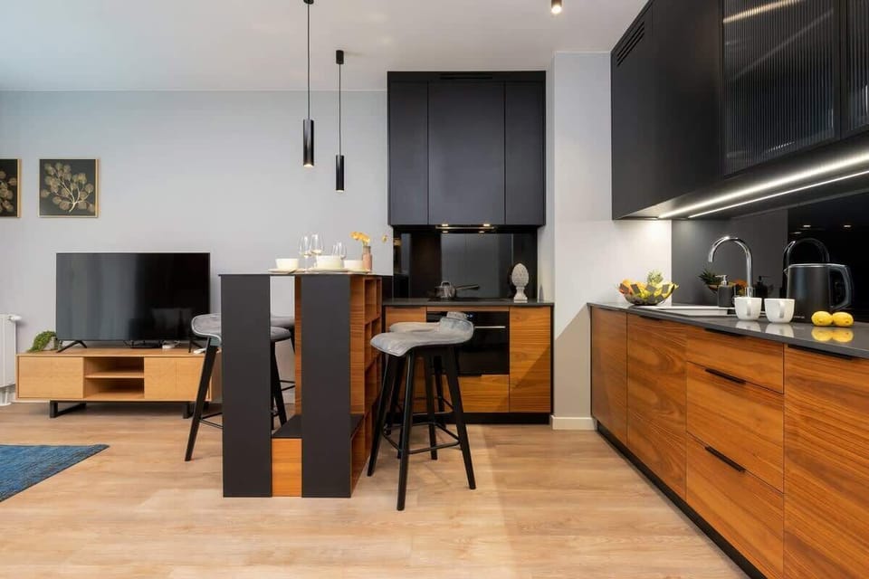 A modern kitchen with wooden cabinetry, black countertops, and an island.