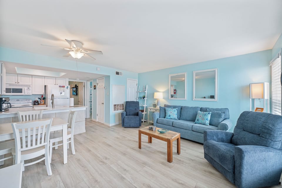 Step into your bright, coastal-inspired living space where soft blue walls and comfortable seating create the perfect atmosphere for relaxation.