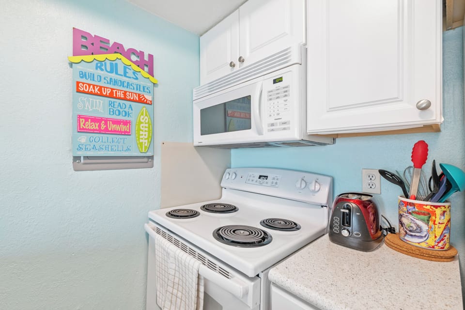 Your fully equipped kitchen awaits with everything you need—stove, microwave, and charming beach-themed touches that set the perfect vacation mood.