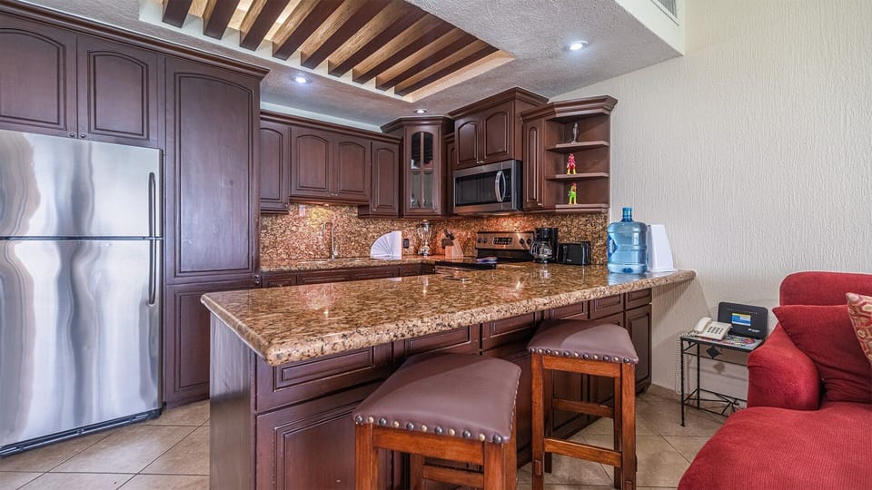 The granite counter of the kitchen blends with the elegant wood cabinetry