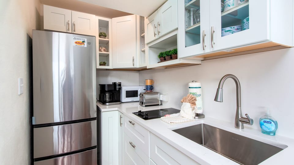 Compact modern kitchenette with brand new stone countertops includes large stainless steel refrigerator, 2-burner stove, microwave, standard and Keurig coffee makers.
