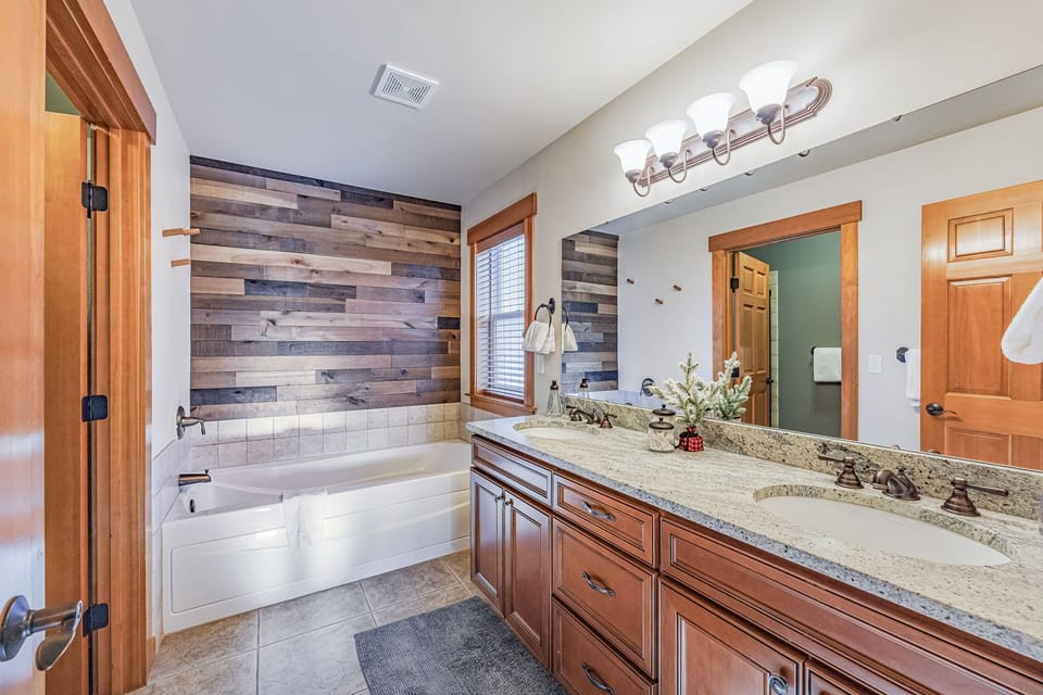 Master En Suite Bathroom with a bathtub and a private shower, toilet room, dual Sink Setup And Warm Wood Cabinetry