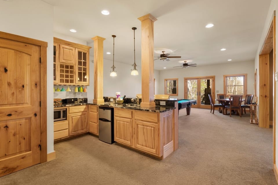 Giant lower level recreation room with wet bar including sink, mini fridge and microwave.  Also features a raised bar with two chairs.