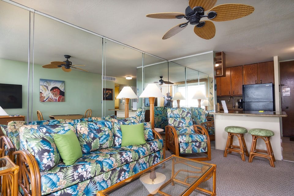 Bright living area with central A/C, a comfortable queen sofa bed, and floor-to-ceiling ocean views.
