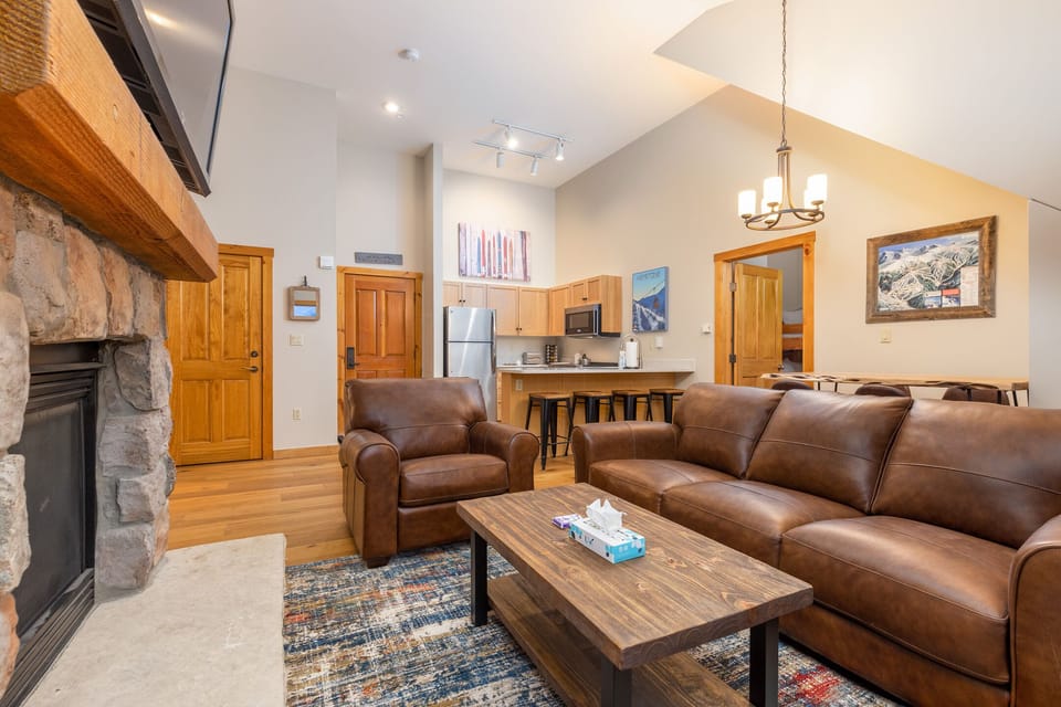 Sink into rich leather seating by your crackling stone fireplace, where mountain artwork and warm wood create your perfect alpine retreat.