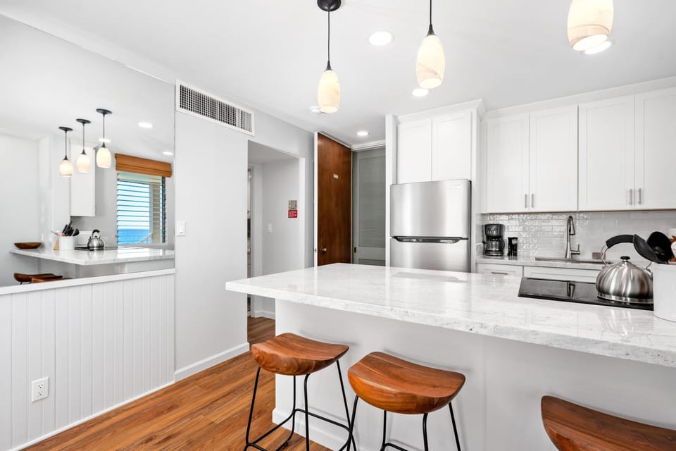 Open kitchen design with brand-new white cabinetry, stainless steel appliances, and everything needed to create meals and beverages in paradise.