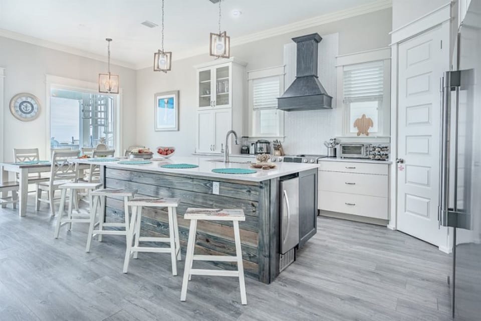 Your bright coastal kitchen invites culinary adventures with gleaming counters, modern appliances, and a rustic island perfect for morning coffee.