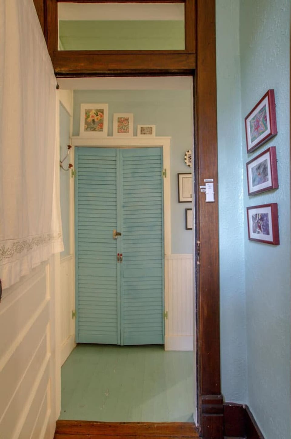 A hallway lined with art and vintage louvered doors leads you through the home.