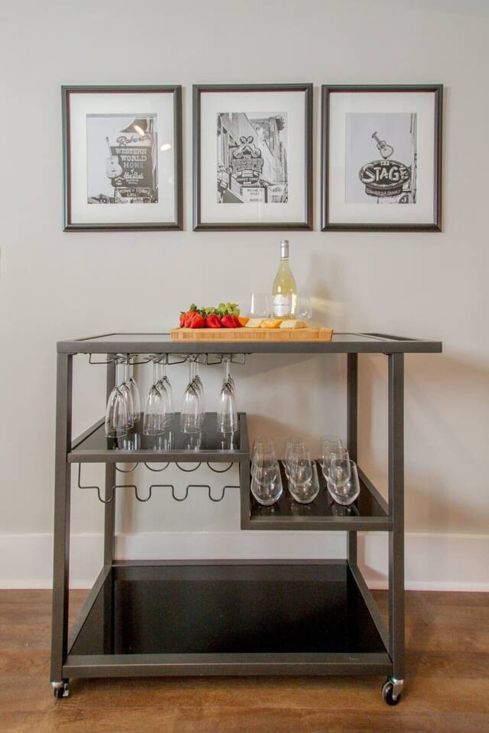 Bar cart with charcuterie board, wine bottle, wine glasses, and framed Nashville art