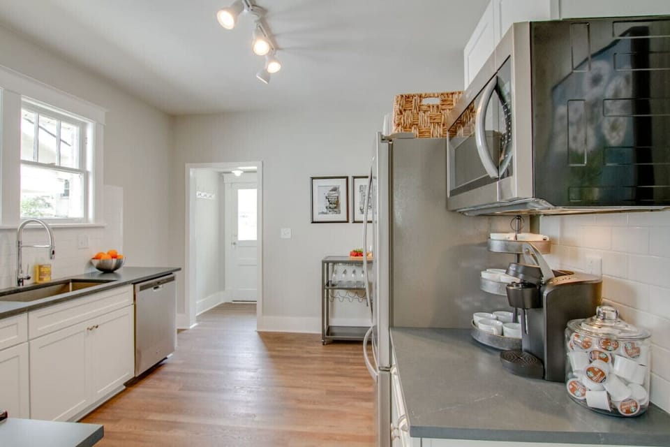 Kitchen with white cabinets, stainless appliances, track lighting, and dark hardwood floors