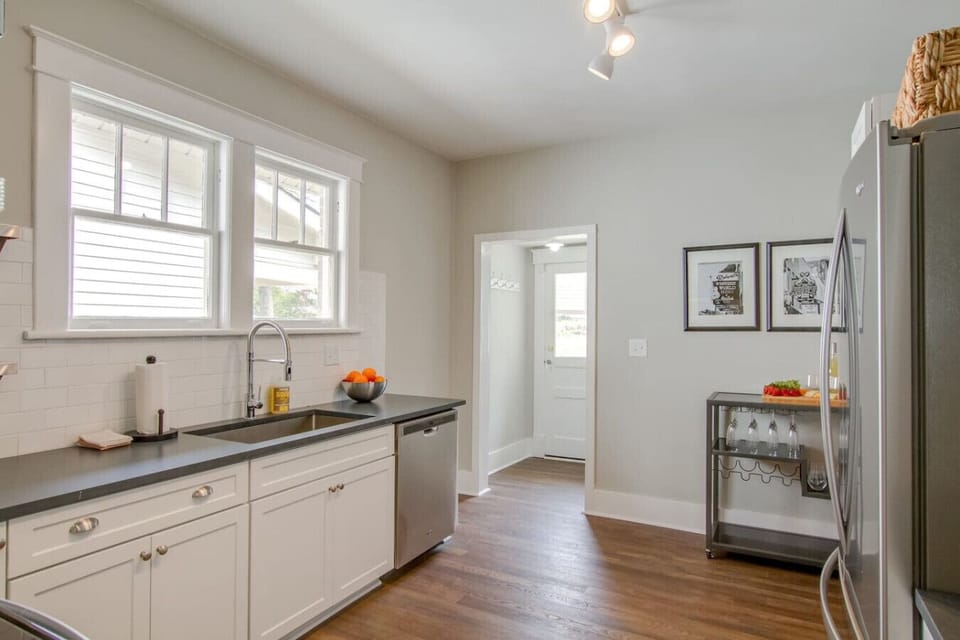 Kitchen countertop with dark granite, orange accent bowl, white cabinets, and appliances