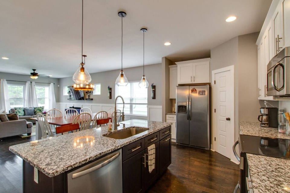 Kitchen with granite island and bar stools, dark wood cabinets, and stainless steel appliances