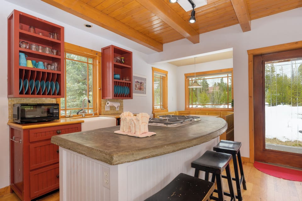 Cook with mountain views through expansive windows in this beautifully appointed kitchen, complete with granite counters and rustic wood beams overhead.