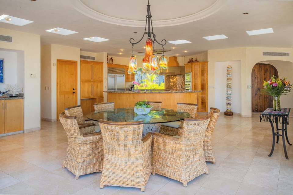 Gather around this stunning glass dining table where natural light streams through skylights, creating the perfect setting for your memorable meals together.