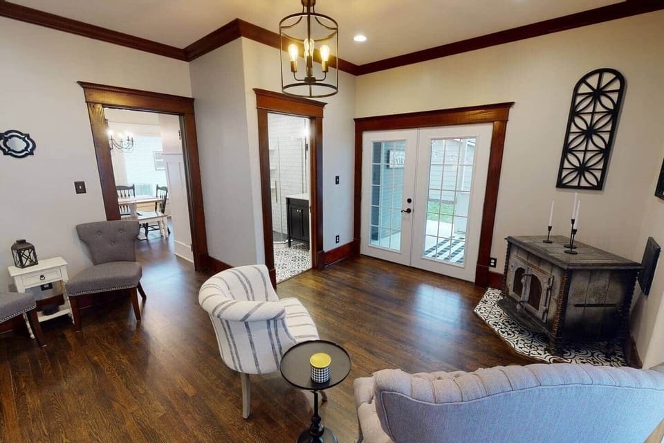 Den with French doors onto patio, 2 seating areas, and fireplace. 