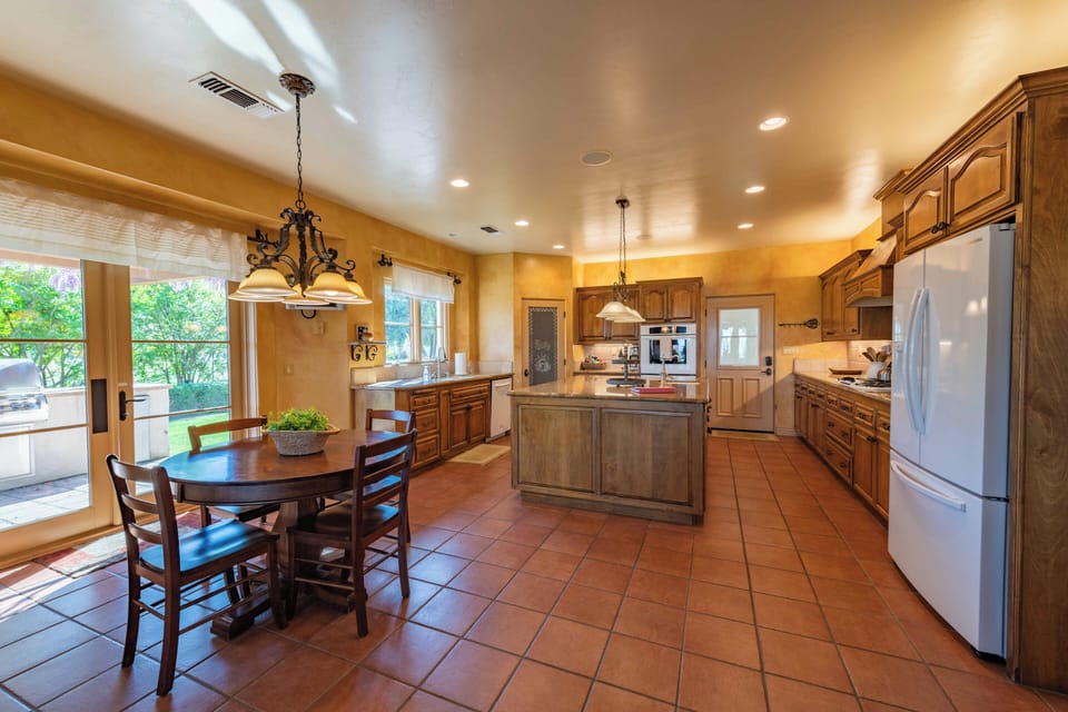 Your fully equipped kitchen features warm wood cabinetry, a spacious island, and elegant dining area where you'll create memorable meals together.