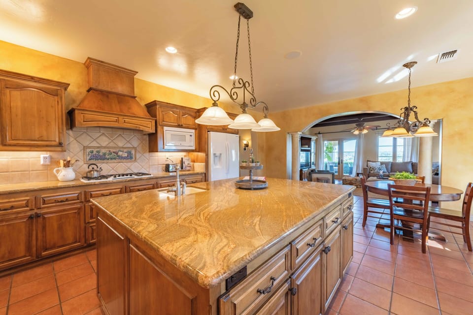 Your spacious gourmet kitchen awaits with rich wood cabinets, granite countertops, and elegant pendant lighting for memorable meal preparation.