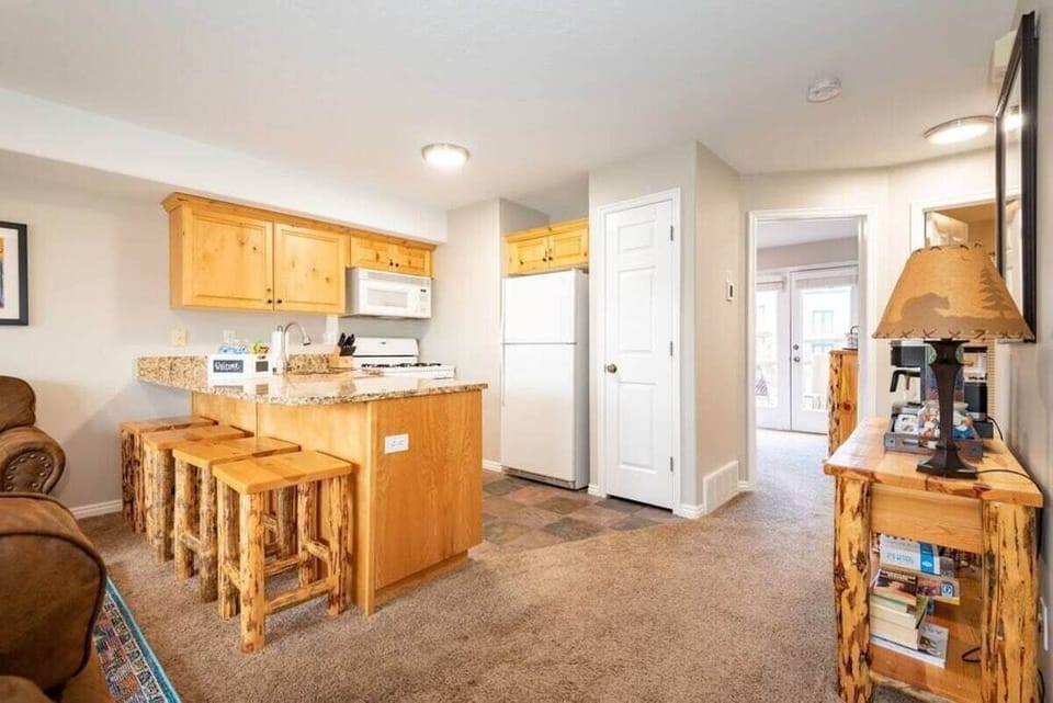 The gourmet kitchen features an island with seating for four and is equipped with appliances, including a microwave, gas stove, and spacious refrigerator.