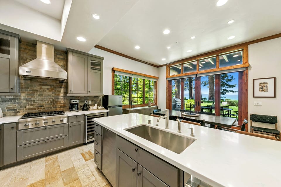 Cook with inspiring forest views through stunning floor-to-ceiling windows in your fully equipped gourmet kitchen with premium appliances and elegant accents.