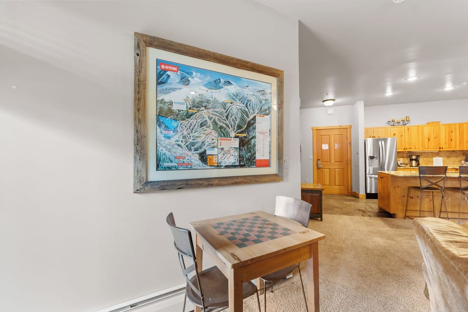 Cozy game corner with checkerboard table where you can unwind after mountain adventures, perfectly positioned near your open kitchen.
