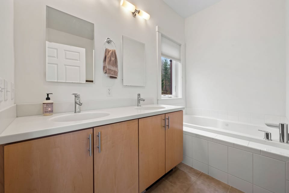 Main floor Master bathroom with double-sink vanity, large tub, and stall shower