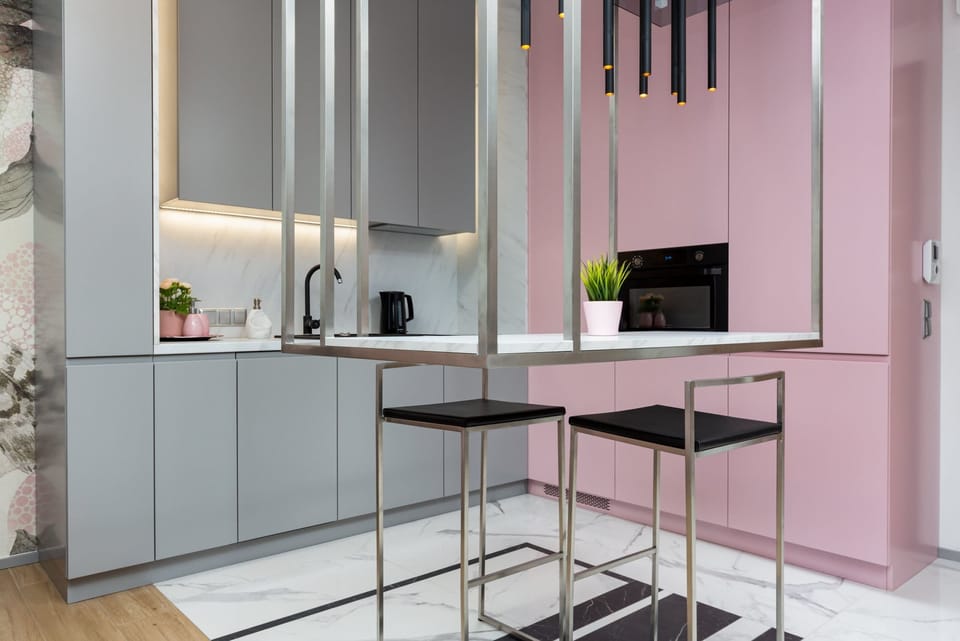 A modern kitchen with gray cabinets, sleek appliances, and an adjoining open space for dining