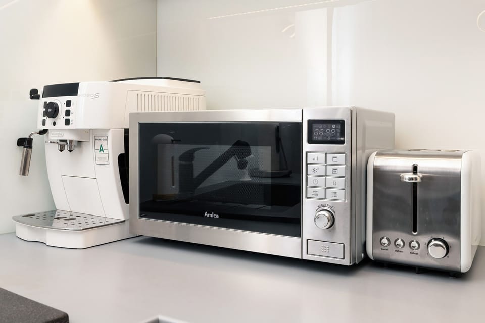 A kitchen corner with a microwave, coffee machine, and other appliances, perfect for quick meals.
