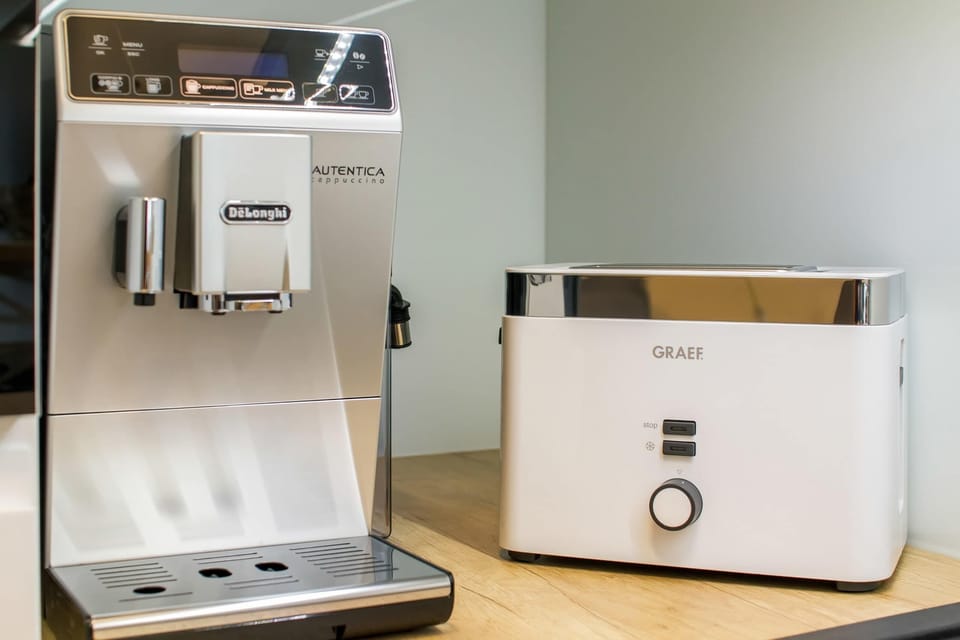 A coffee cornerwith a high-end espresso machine and toaster, set on a light-colored countertop, making an ideal spot for morning routines.