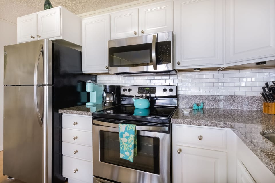 Kitchen view with coffee maker, Keurig, microwave, and range.