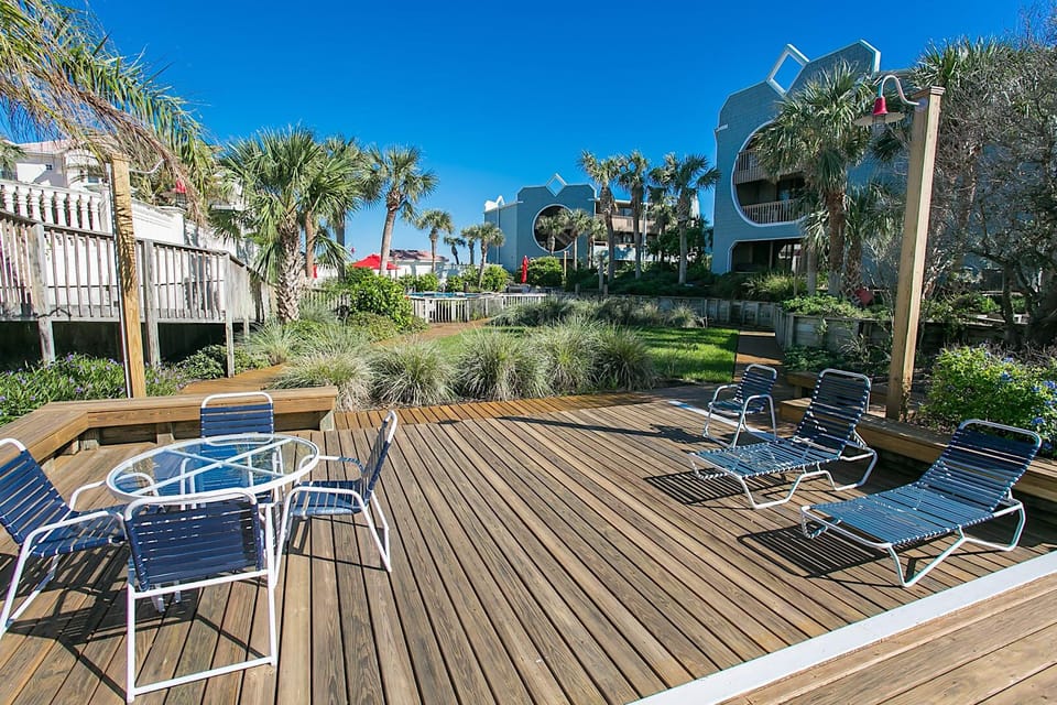 Spacious wooden deck with loungers and seating amid a tropical courtyard.