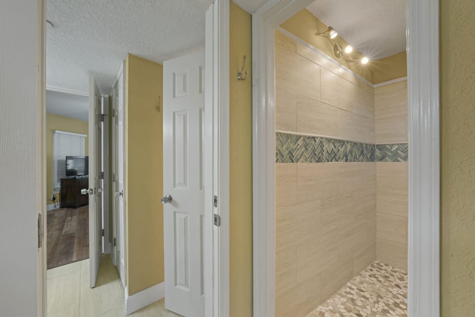 Stylish guest shower with designer tile, pebble-style flooring, and bright lighting for a spa-like experience.
