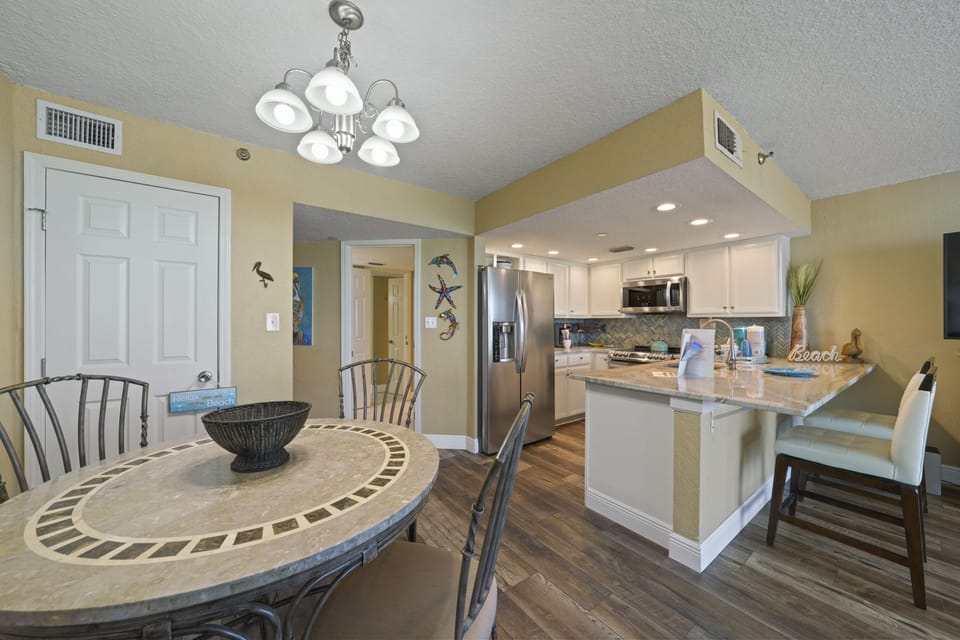 This bright and inviting vacation rental offers an open kitchen with stainless appliances, custom backsplash, and breakfast bar. The cozy dining space makes it easy to gather and enjoy meals together.