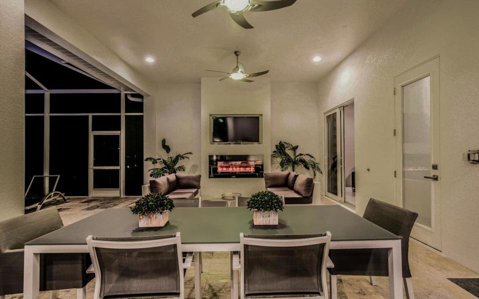 Covered outdoor dining and living area with modern dining table, chairs, and a fireplace, perfect for al fresco entertaining