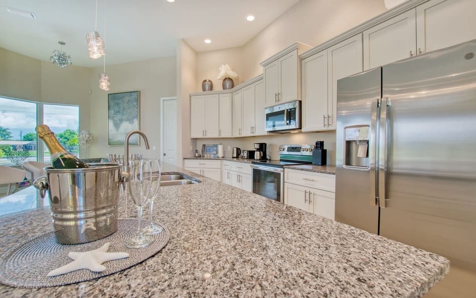 Kitchen featuring white cabinets, stainless refrigerator, and granite island