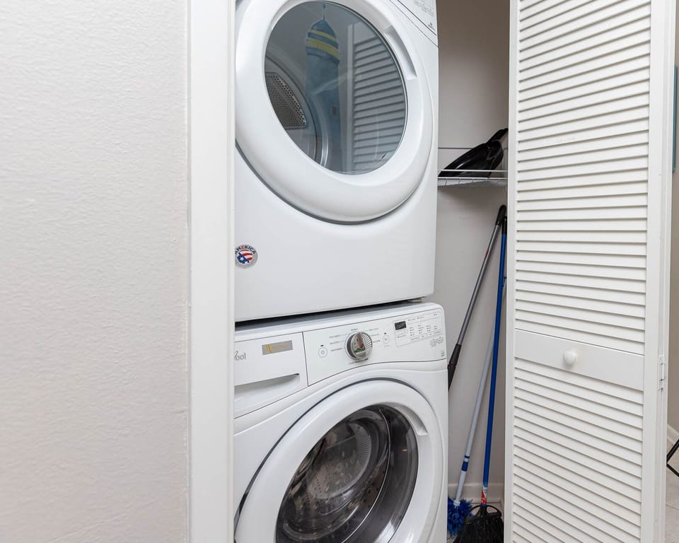 Stacked washer and dryer provide convenient laundry access, complemented by storage space for cleaning supplies