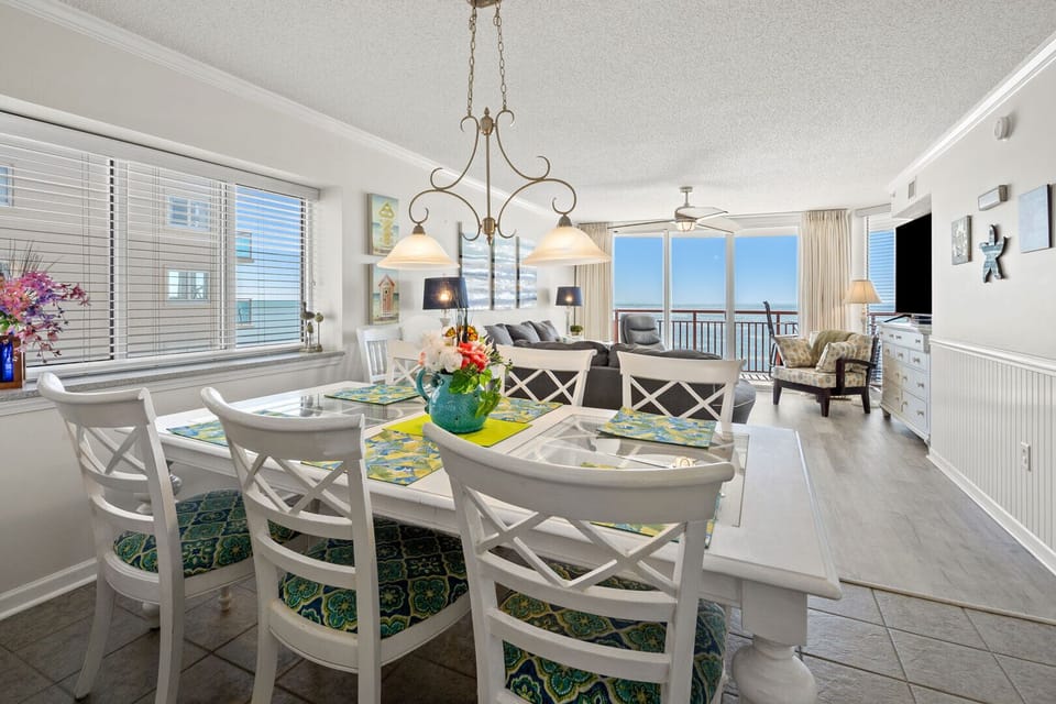 Dining table under a chandelier with balcony doors and ocean views at South Shore Villas 701, Crescent Beach