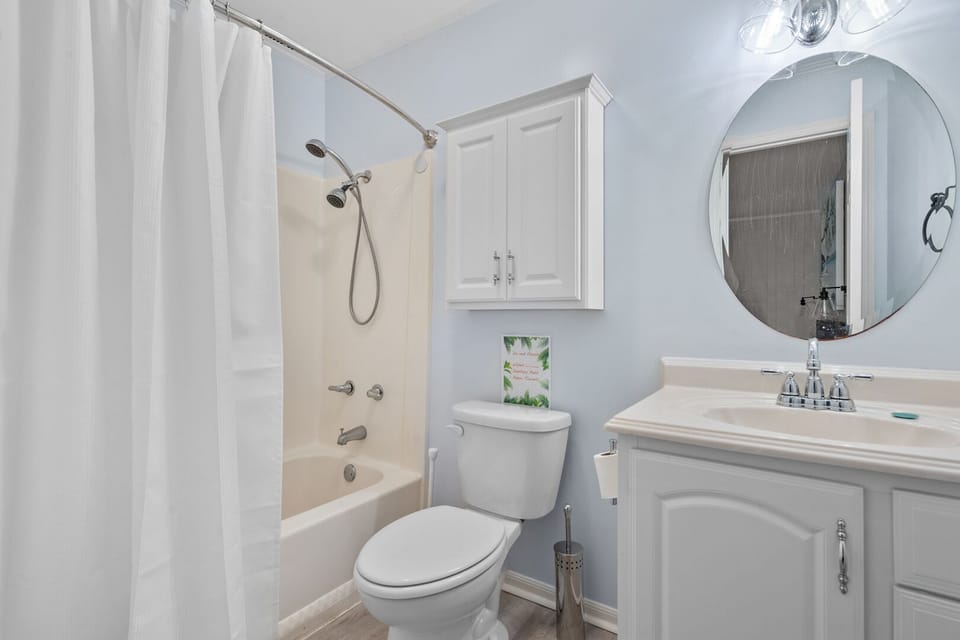 Bathroom with a round mirror, vanity and curtained shower at Sun Villas A1 in North Myrtle Beach