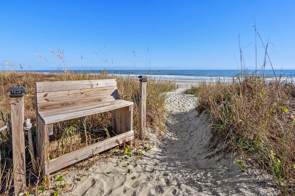 Bench on the sandy path with ocean views at Sun Villas A1, a 2-bedroom Crescent Beach vacation rental