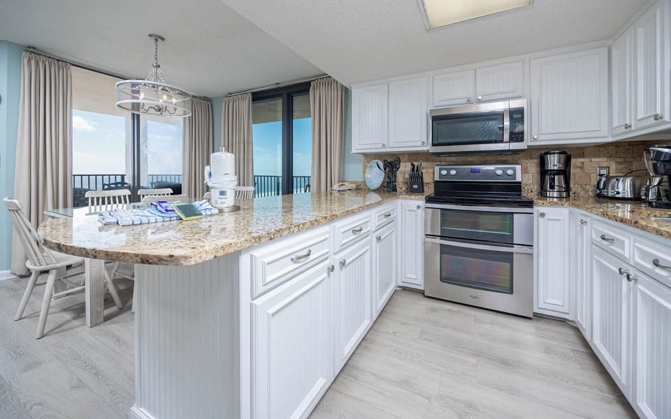 Prepare meals in the spacious kitchen featuring a large breakfast bar, stainless appliances, and beachfront views