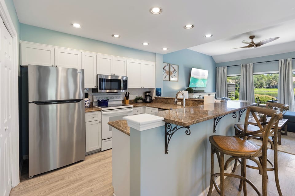 Gather around the granite island in this fully equipped kitchen, where stainless steel appliances and coastal blue hues create a bright, welcoming space for cooking and conversation.