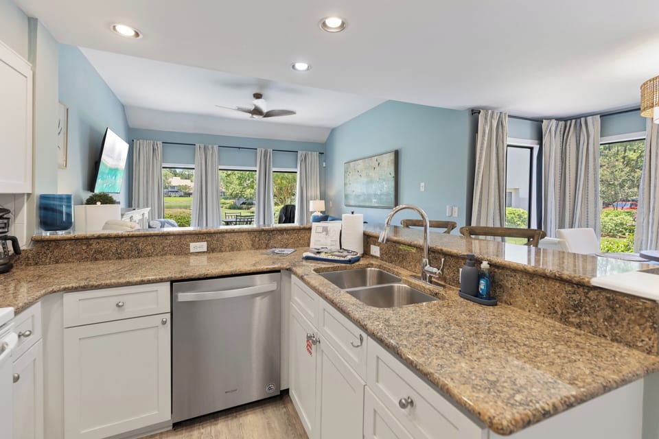 Picture yourself cooking in this bright, open kitchen with sparkling granite counters and modern appliances. Soothing blue walls frame windows showcasing a lush garden, perfect for your morning coffee or evening meal prep.