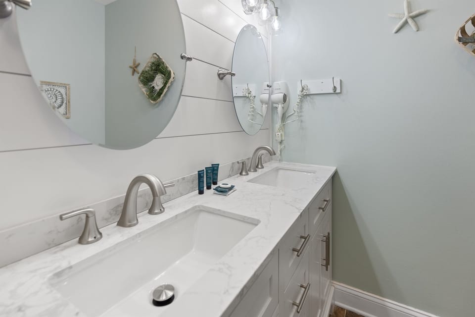 Your spacious dual-sink vanity provides ample counter space and storage, with charming coastal touches throughout this pristine bathroom.