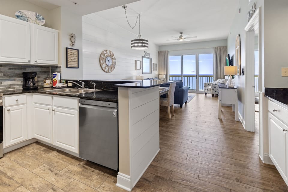 Your bright kitchen flows seamlessly into the living area, where ocean views await through floor-to-ceiling windows.