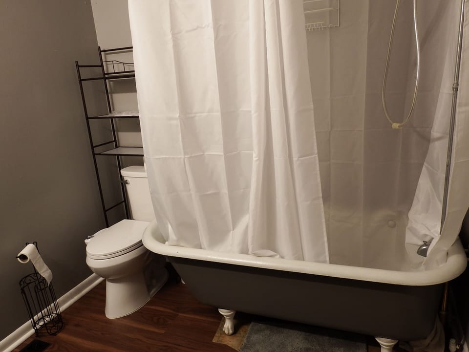 View of the right side of the bathroom. Note clawfoot tub only set up for shower