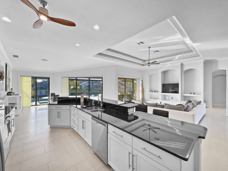 Kitchen with large dark granite island, sink, and white cabinetry