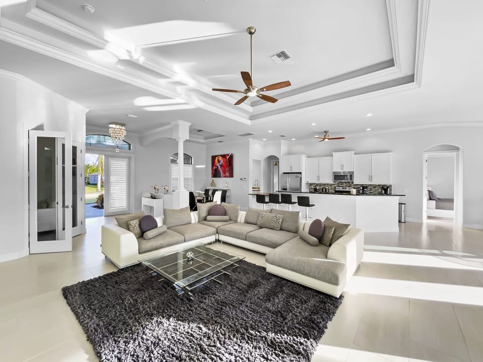 Open-concept living room and kitchen with sliding glass doors to the pool